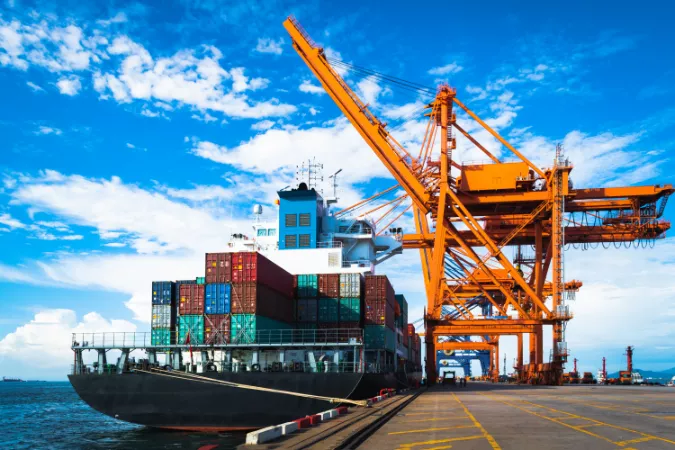 A large container ship loading containers at the port terminal, in which they would have to comply with the UK working at height regulations.