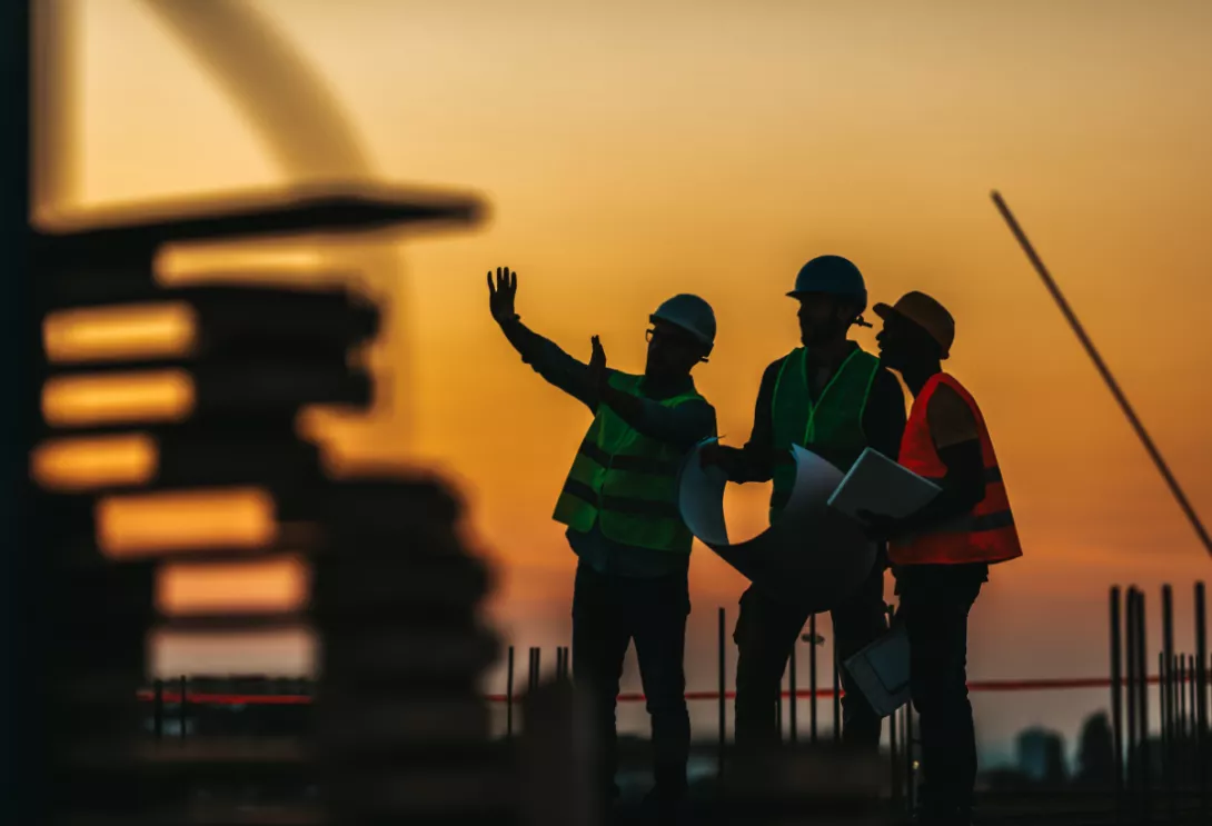 Construction workers evaluating how they can lift heavy loads with the use of a portable gantry. 