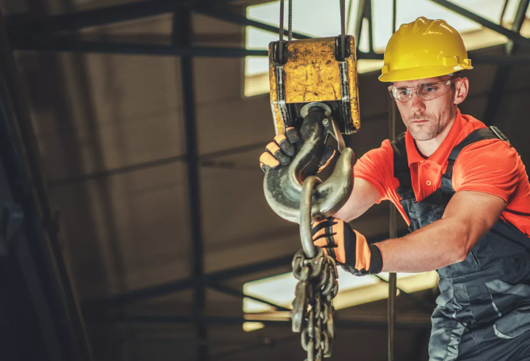  A construction worker using a piece of lifting equipment, an overhead crane in a construction warehouse. 